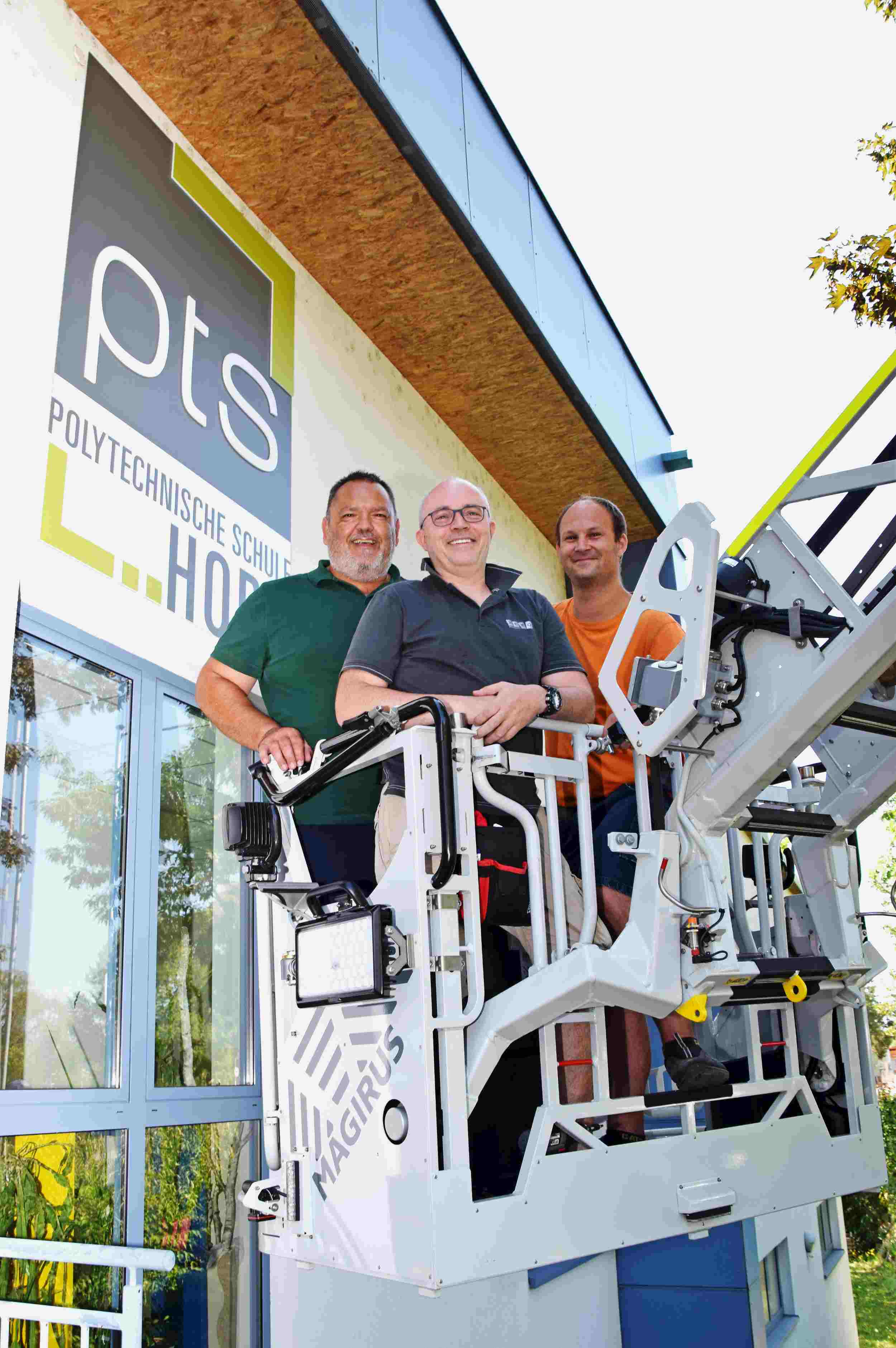 Schulwart Sascha Drlo, Andreas Rehart von Remo Horn und Florian Waldschütz vom Wirtschaftshof freuen sich über die mit Logo neu gestaltete Außenfassade. Foto: Gabriele Hohenegger